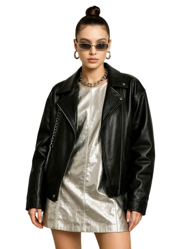 Woman wearing a black leather jacket over a metallic silver mini dress on a white background